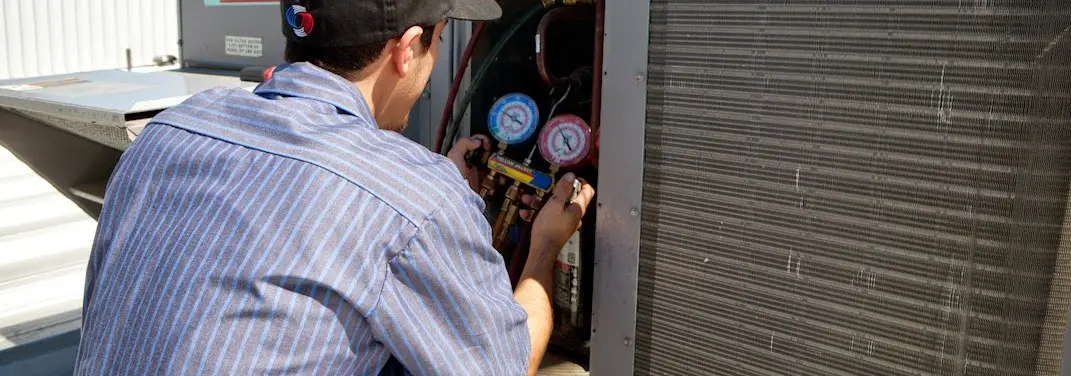 HVAC technician servicing a condenser unit in Grosse Pointe Park
